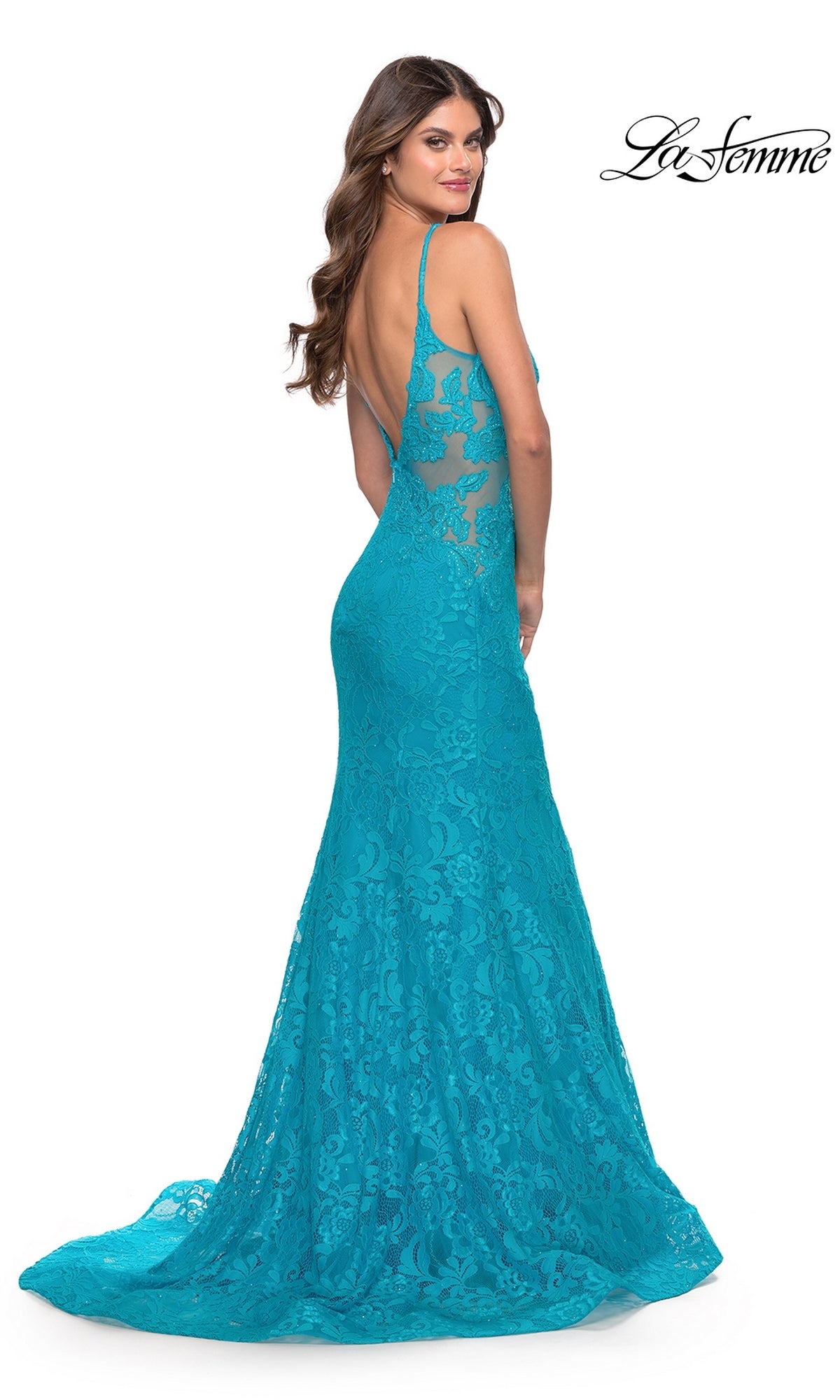 A woman poses with her back to the camera in the Long Lace Mermaid Prom Dress: La Femme 31512, a bright turquoise lace gown with a low back and thin straps. The